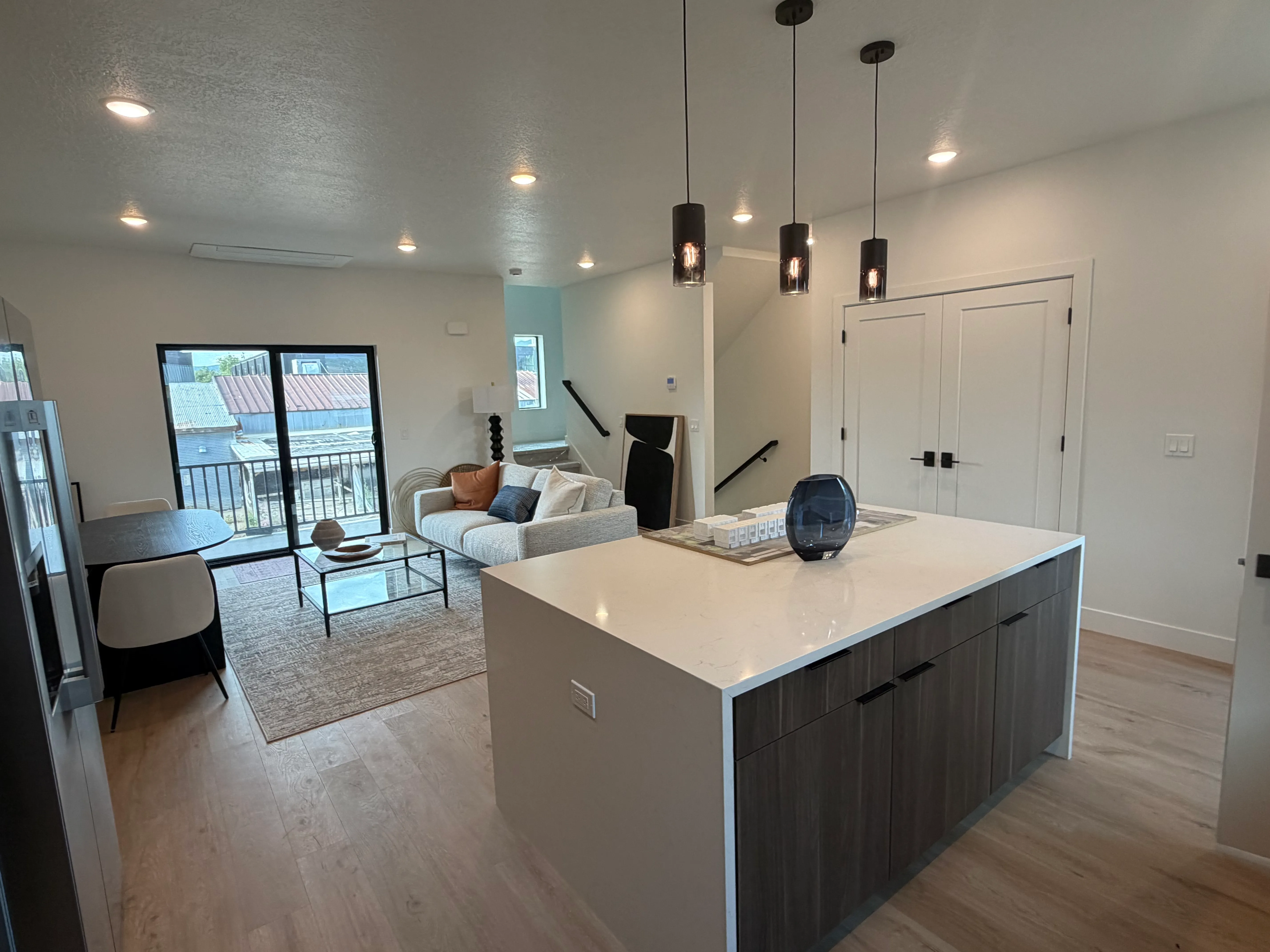Kitchen island and living area furnished, with a dining nook beside the sliding door to the balcony
